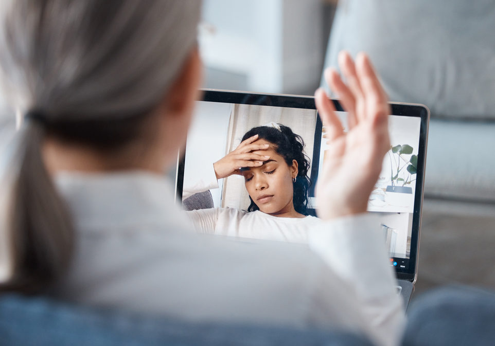 an unrecognisable psychologist sitting and using a laptop for an online consultation with her patient.